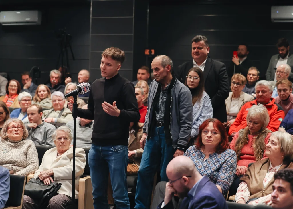 Uczestnik spotkania z mikrofonem argumentujący w trakcie otwartej dyskusji.
